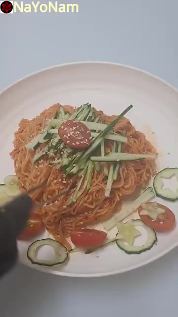 깨를 뿌려 비빔국수를 완성한다. — 매콤달콤 비빔국수 만들기