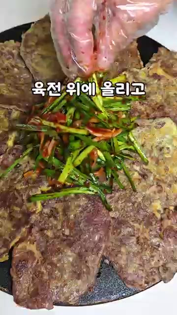 구워진 육전 위에 부추무침을 올리고 통깨를 뿌려 완성한다. — 급식대가 육전&부추무침 레시피