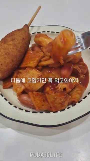 떡볶이를 포크로 집어 먹는다. — 떡볶이에 핫도그