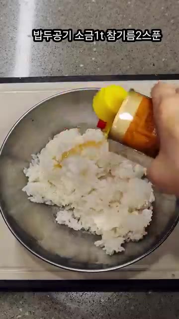 밥 두 공기에 소금 1작은술, 참기름 2큰술을 넣고 잘 섞어줍니다. — 중독위험 스팸 땡초김밥