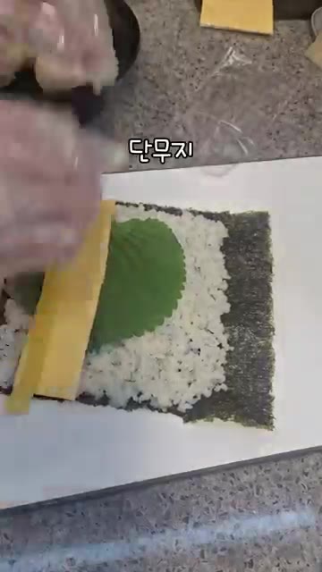 김밥용 김 위에 밥을 얇게 펴고 깻잎, 슬라이스 치즈, 단무지, 게… — 안키모와 도다리 회무침