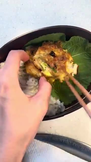 도시락 통에 밥과 깻잎을 깔고 부친 버섯 참치전을 올린다. — 버섯 참치전 도시락 만들기