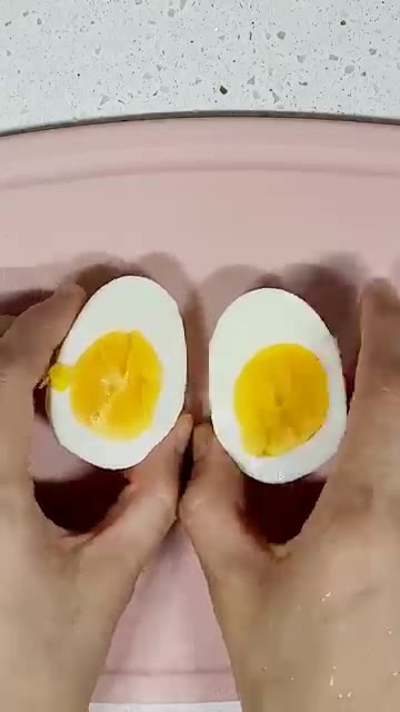 삶은 달걀을 찬물에 식힌 후 껍질을 벗겨 반으로 자른다. — 천연 위고비 식단: 올리브 오일, 단호박, 토마토, 달걀을 곁들인 건강한 아침 식단