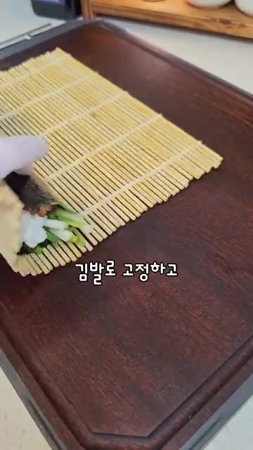 김발을 이용해 단단하게 만다. 김밥 위에 참기름을 바른다. — 고등어 김밥 레시피