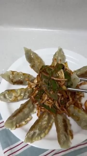 구운 만두 위에 버무린 채소를 올리고 깨를 뿌려 완성한다. — 새콤달콤 비빔만두 이렇게 해보세요