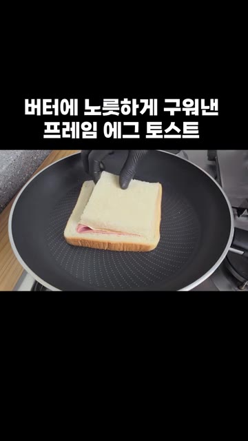 식빵 가운데 빈 공간에 슬라이스 햄을 올리고 계란을 깨뜨려 넣습니다. — 버터에 노릇하게 구워낸 프레임 에그 토스트