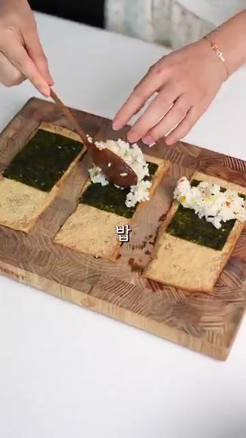 유부에 김을 깔고 밥, 양배추 무침, 계란을 올려 돌돌 말아준다. — 양배추 유부초밥 레시피