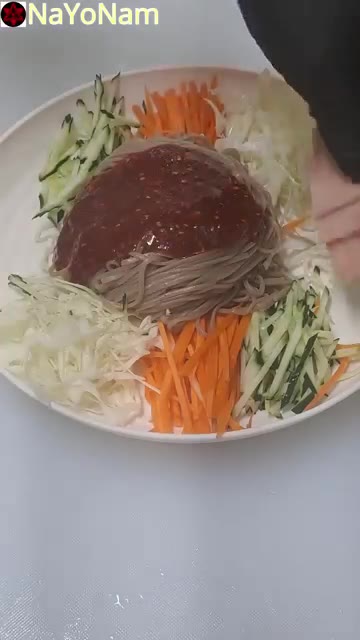 넓은 그릇에 메밀면을 담고 채 썬 오이, 당근, 양배추를 올린다. — 매콤달콤 비빔막국수 만들기