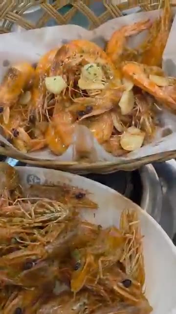 버터에 익힌 새우 머리를 접시에 담는다. — 싱싱한 새우 소금구이와 버터구이