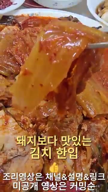 잘 익은 돼지고기 김치찜 한 점을 집어 맛을 본다. — 집밥 한상차림: 돼지김치찜, 생선구이, 쌈채소 등